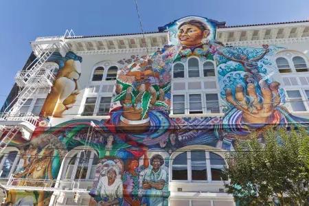 Ein farbenfrohes, großformatiges Wandgemälde bedeckt die Seite des Women's Building im 目标区 von San Francisco.